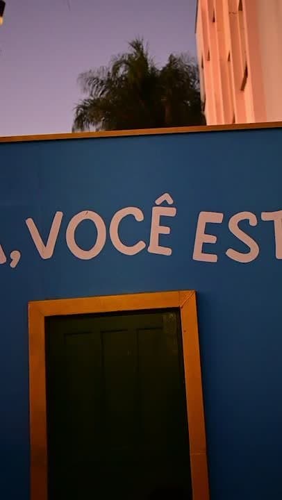 Fachada azul ao entardecer com letreiro em rosa.